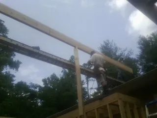 Carpenter setting a ridge beam over a new addition frame — Ice Dam Removal by Roofing Brothers in Grundy Center