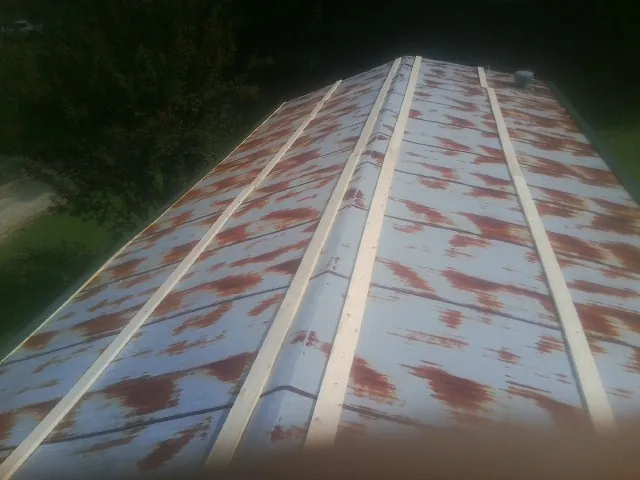 Rusted metal roof panels with new wood purlins before replacement — Storm Damage Roof Repair in Grundy Center by Roofing Brothers