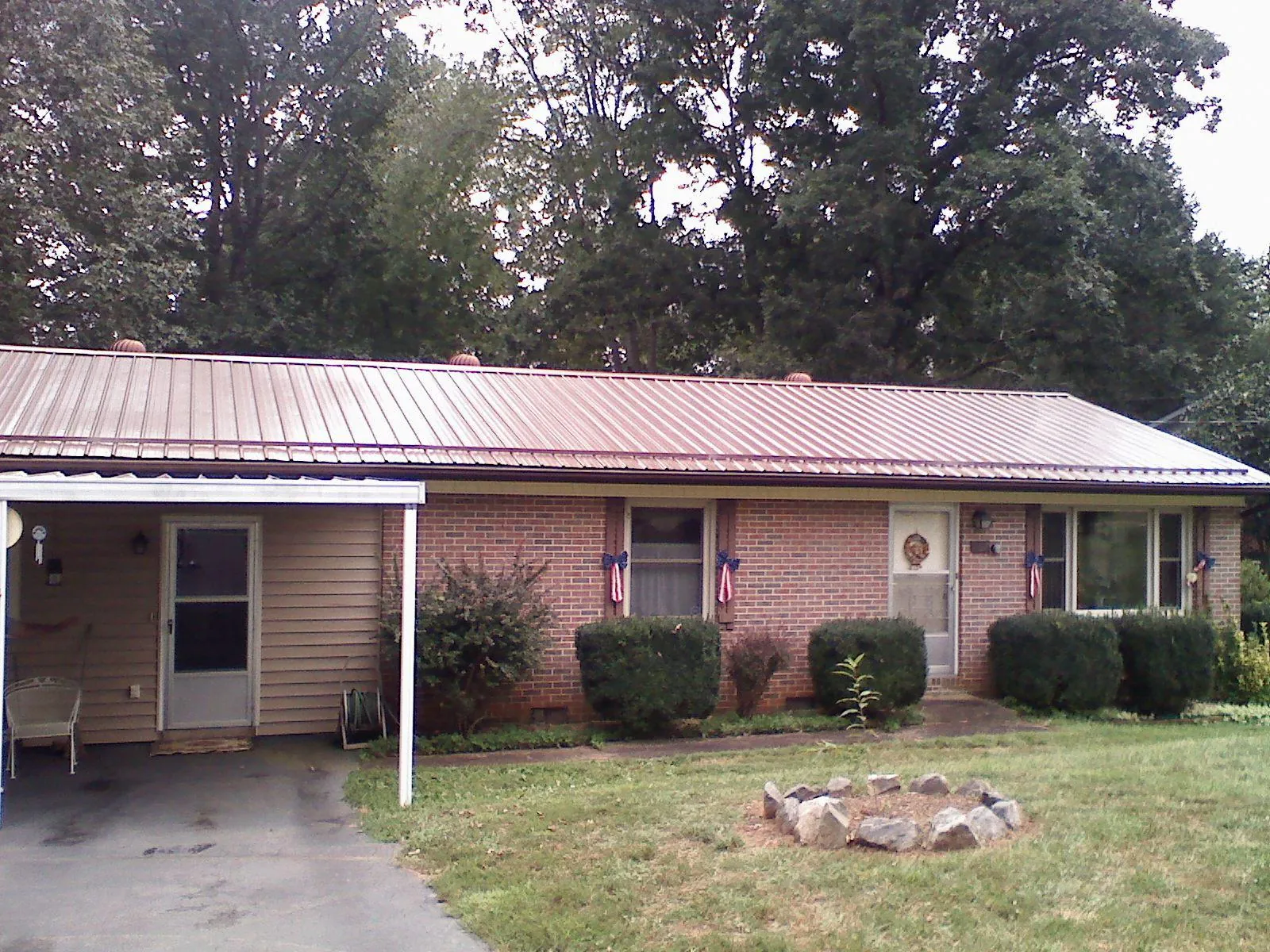 Bronze metal roof and carport on a brick ranch home — Roof Repair work by our crew in Grundy Center