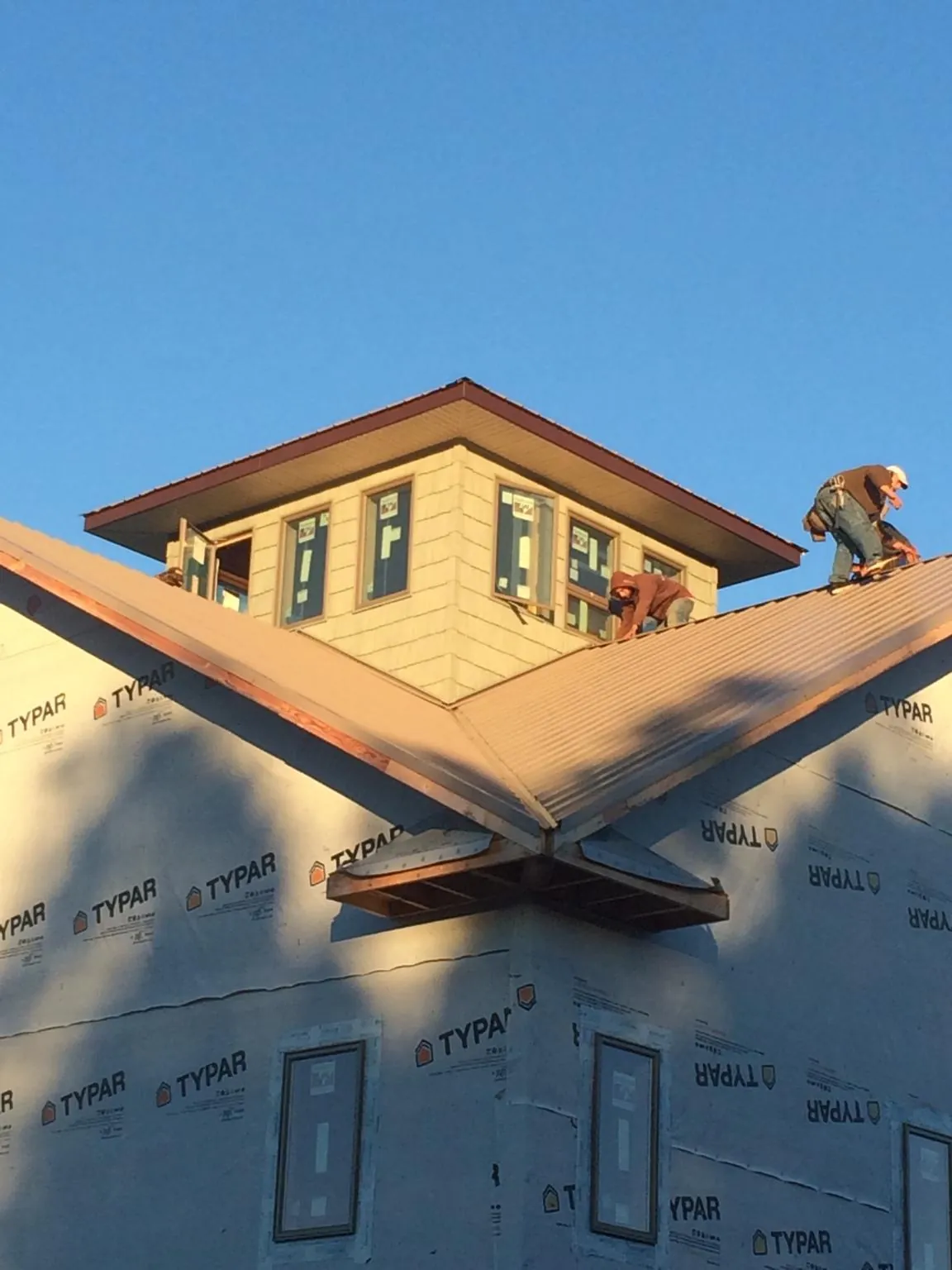 Roofers working around a rooftop cupola on a new metal roof at sunset — Roof Waterproofing in Grundy Center by Roofing Brothers